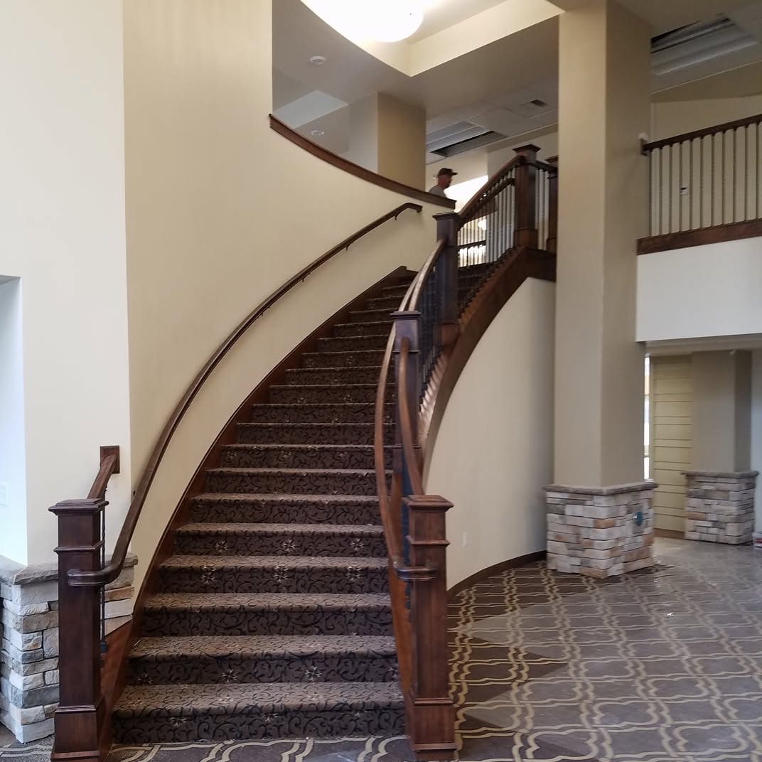 A curved staircase with hardwood treads and a wooden handrail