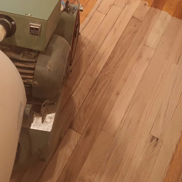 A drum sander part way through sanding a hardwood floor